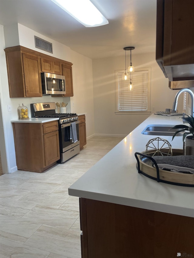 kitchen featuring visible vents, a sink, stainless steel appliances, light countertops, and brown cabinets