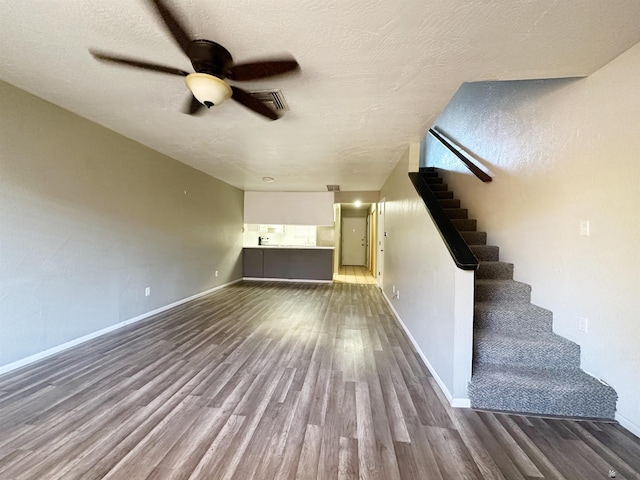 unfurnished living room with ceiling fan, hardwood / wood-style floors, and a textured ceiling