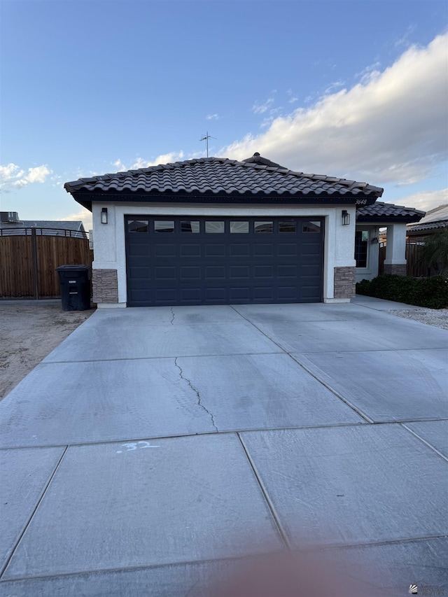 view of front of property with stone siding, fence, driveway, and stucco siding