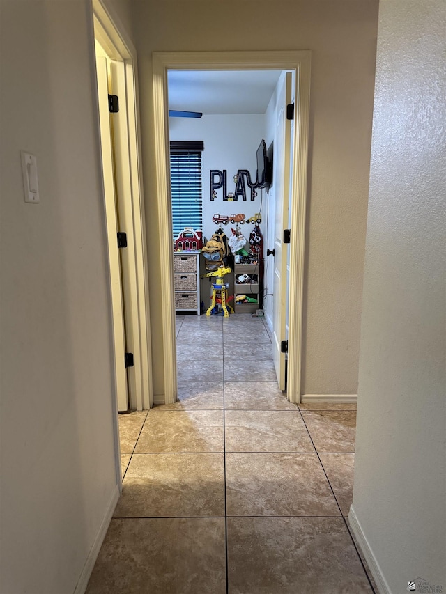 hallway with light tile patterned floors and baseboards