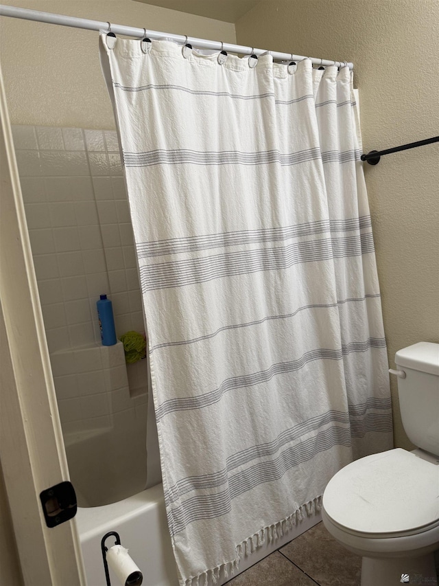 bathroom with a textured wall, shower / bathtub combination with curtain, toilet, and tile patterned floors