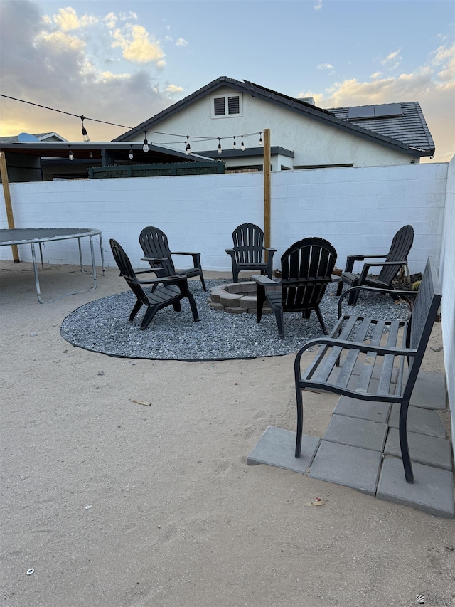 patio terrace at dusk featuring an outdoor fire pit and fence