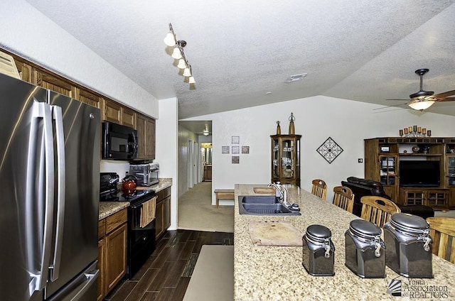 kitchen featuring a textured ceiling, vaulted ceiling, ceiling fan, sink, and black appliances