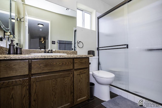 bathroom with vanity, toilet, and a shower with shower door