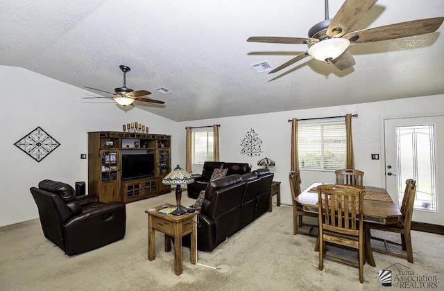 living room with a textured ceiling, light carpet, and lofted ceiling