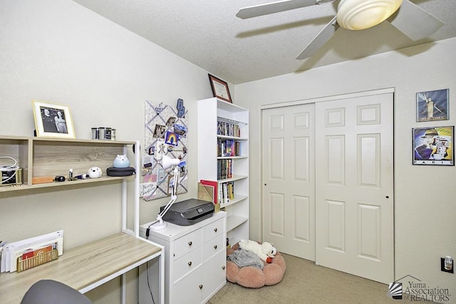 carpeted office featuring ceiling fan and a textured ceiling