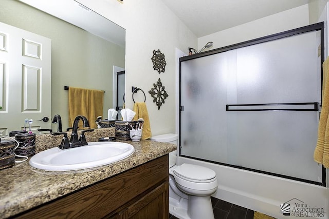 full bathroom featuring combined bath / shower with glass door, vanity, and toilet