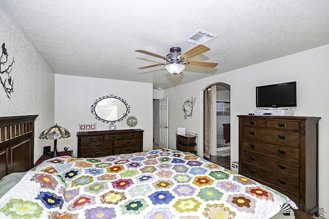 bedroom featuring ceiling fan, a textured ceiling, and ensuite bath