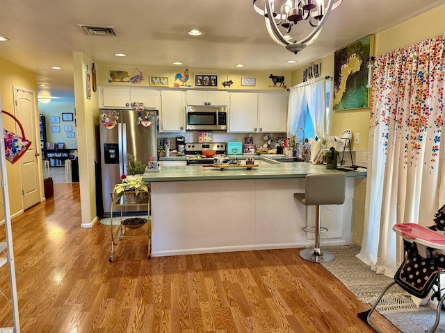 kitchen featuring sink, white cabinetry, light wood-type flooring, kitchen peninsula, and stainless steel appliances