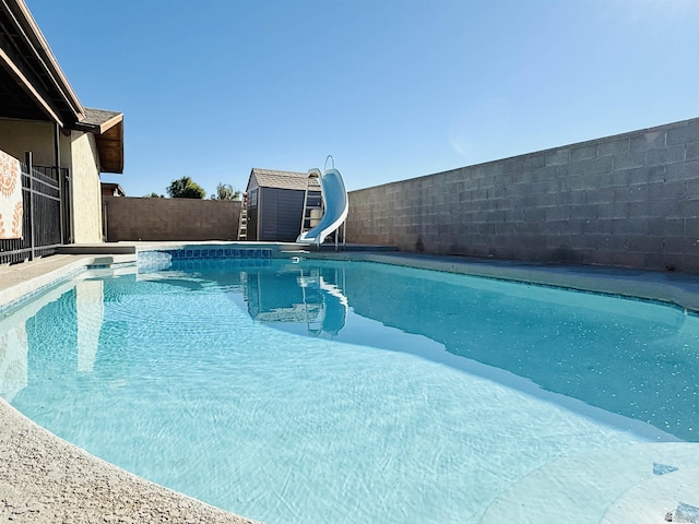 view of pool with a water slide and a shed