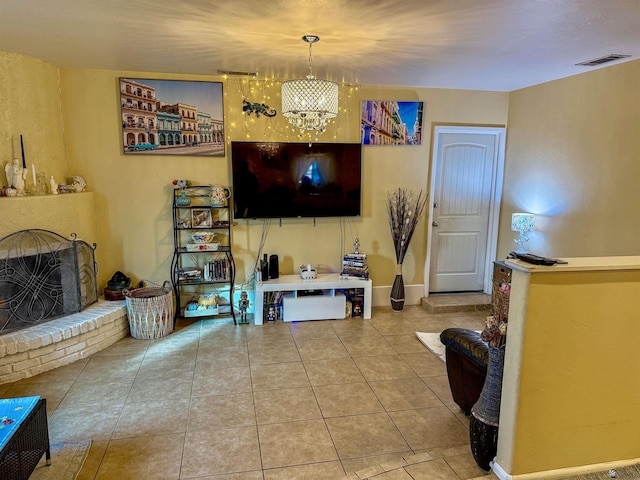 living room featuring tile patterned floors, a brick fireplace, and a notable chandelier