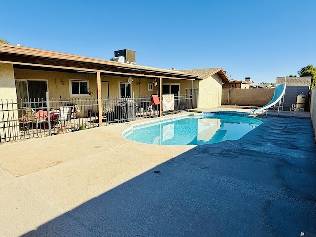 view of swimming pool with a water slide and a patio