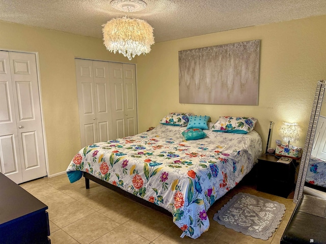 tiled bedroom with a notable chandelier and a textured ceiling