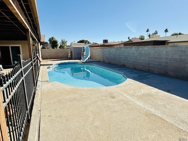 view of pool featuring a shed, a patio, and a water slide