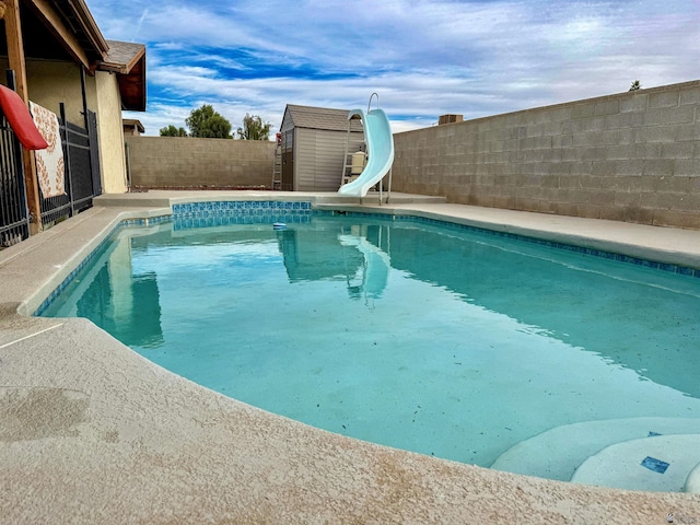 view of swimming pool featuring a shed and a water slide