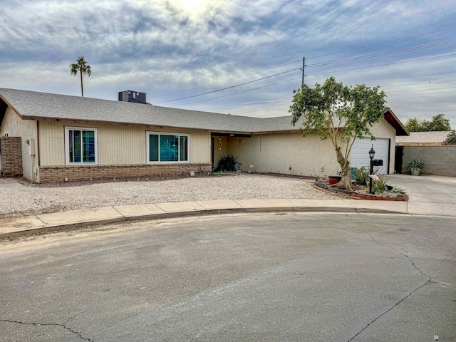 ranch-style home featuring a garage and central AC unit