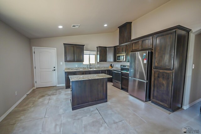 kitchen featuring vaulted ceiling, dark brown cabinets, a kitchen island, light stone counters, and stainless steel appliances