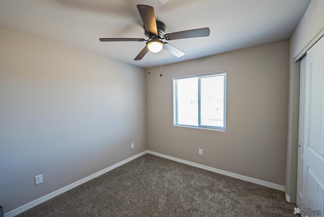 unfurnished bedroom featuring ceiling fan, dark carpet, and a closet