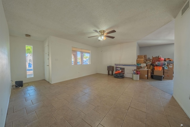 empty room featuring ceiling fan, light tile patterned floors, and a textured ceiling