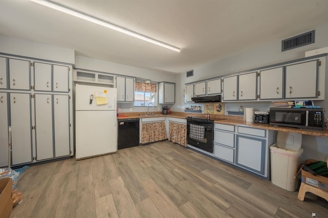 kitchen with gray cabinetry, sink, black appliances, and light wood-type flooring