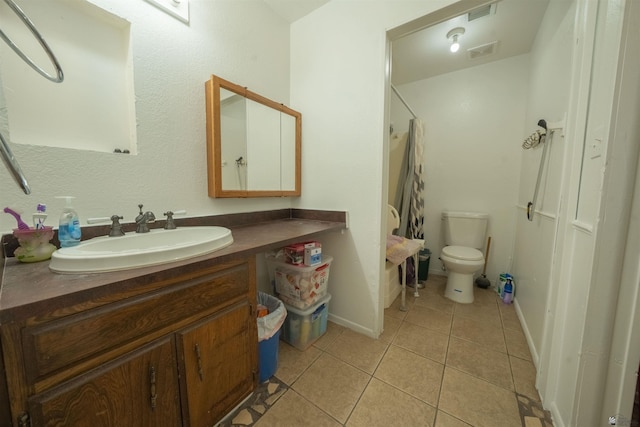 bathroom with tile patterned floors, walk in shower, vanity, and toilet