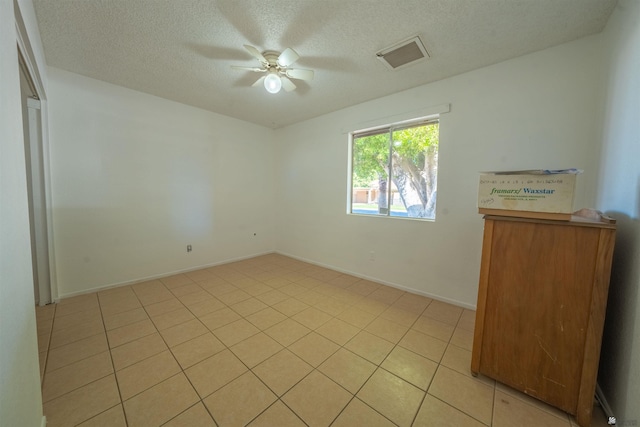 spare room with light tile patterned floors, a textured ceiling, and ceiling fan