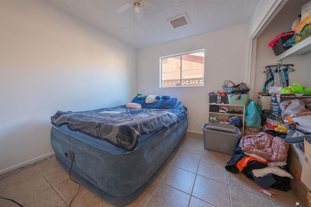 tiled bedroom featuring ceiling fan and a textured ceiling