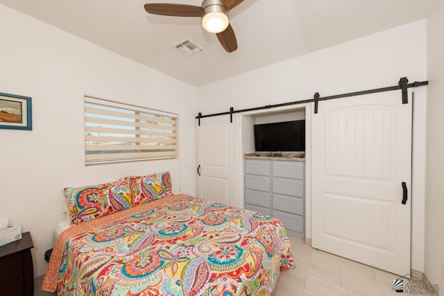 bedroom with a barn door, visible vents, and a ceiling fan