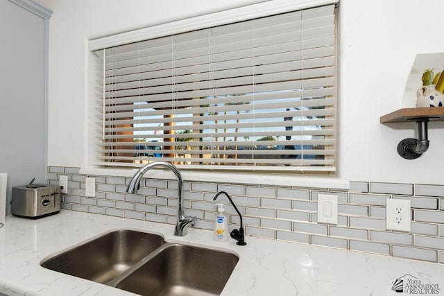 room details with a sink, open shelves, decorative backsplash, and light stone countertops