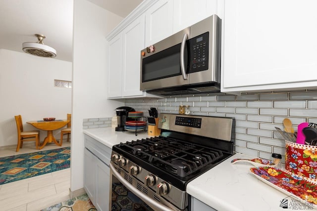 kitchen featuring stainless steel appliances, light countertops, white cabinetry, and decorative backsplash