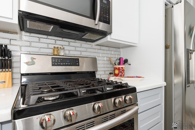 kitchen with stainless steel appliances, white cabinets, light countertops, and decorative backsplash