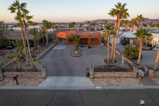 view of front facade featuring a fenced front yard, a residential view, decorative driveway, and a mountain view