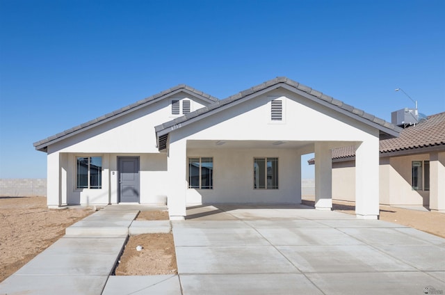 view of front of house featuring stucco siding, a tiled roof, fence, a carport, and concrete driveway