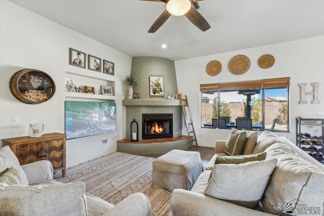 living area featuring a fireplace and a ceiling fan