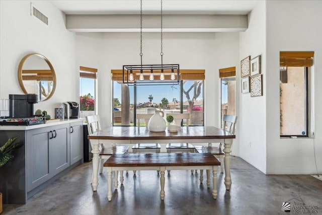 dining space featuring concrete flooring, visible vents, and a towering ceiling