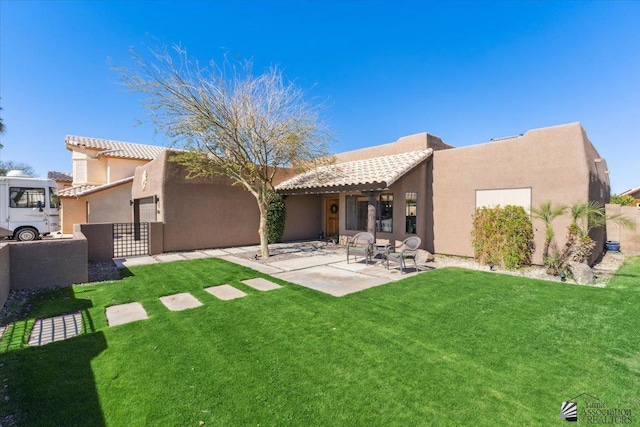 rear view of house with a yard, a patio area, a tile roof, and stucco siding