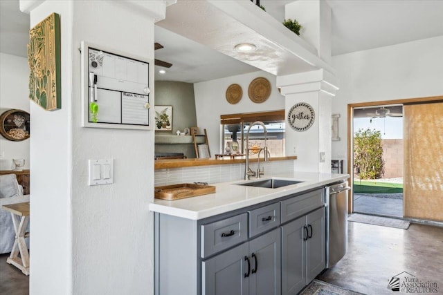 kitchen featuring tasteful backsplash, a sink, gray cabinets, concrete flooring, and stainless steel dishwasher