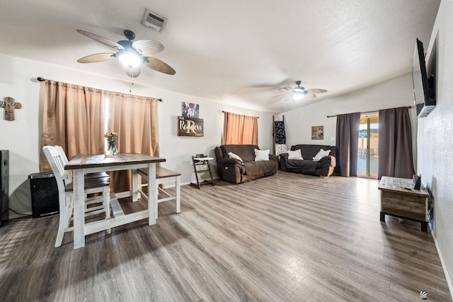 living room with ceiling fan, a textured ceiling, wood finished floors, and visible vents