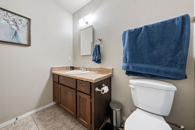 half bathroom with toilet, tile patterned flooring, baseboards, and vanity