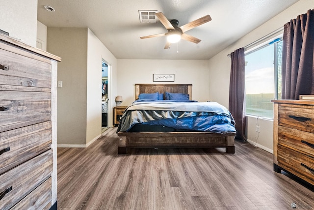 bedroom featuring visible vents, ceiling fan, baseboards, and wood finished floors