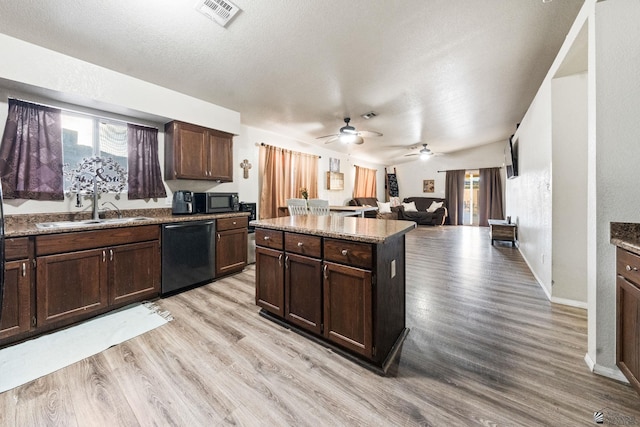 kitchen with dark brown cabinetry, a sink, open floor plan, black appliances, and light wood finished floors