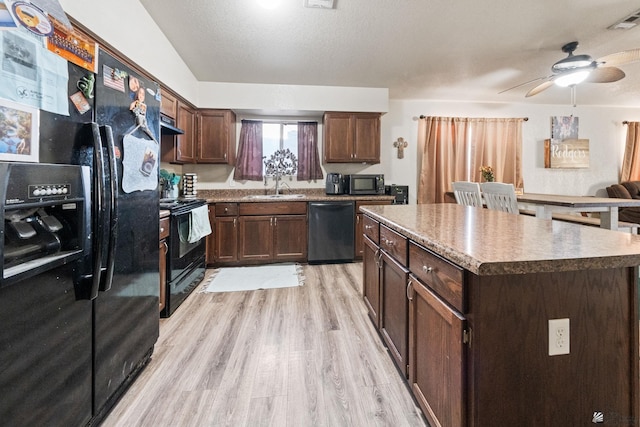 kitchen with a center island, visible vents, light wood-style flooring, a sink, and black appliances