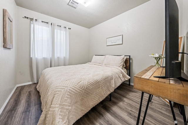 bedroom with dark wood-style floors, visible vents, a textured ceiling, and baseboards