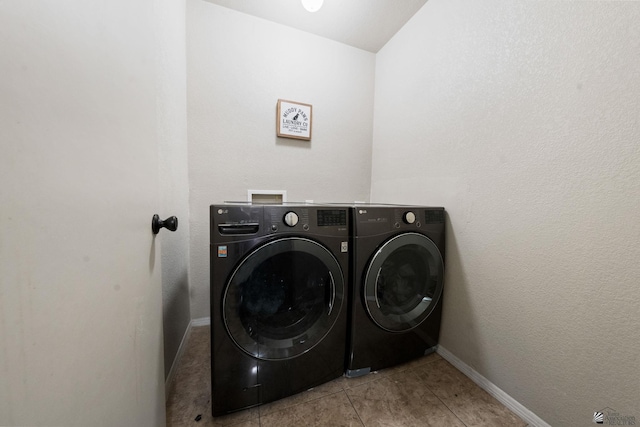 laundry room with light tile patterned floors, laundry area, washing machine and dryer, and baseboards