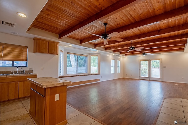 kitchen with sink, tile countertops, a center island, wooden ceiling, and beamed ceiling