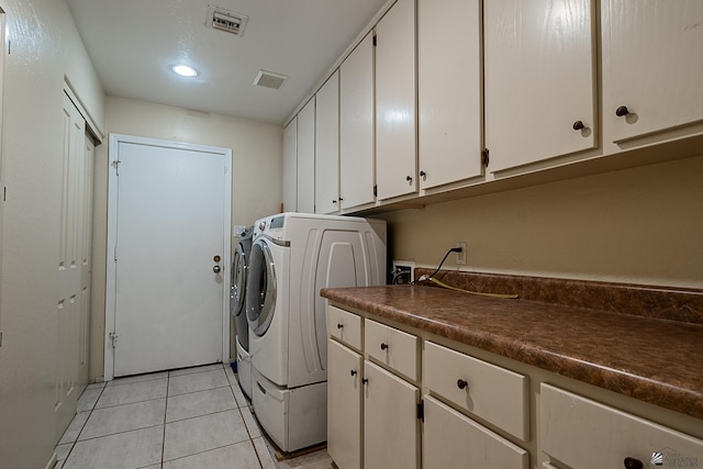 laundry area featuring cabinets, light tile patterned flooring, and washer and clothes dryer