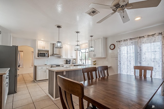 kitchen featuring white cabinetry, appliances with stainless steel finishes, and wall chimney exhaust hood