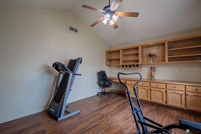 exercise area with vaulted ceiling, built in desk, ceiling fan, and dark hardwood / wood-style flooring