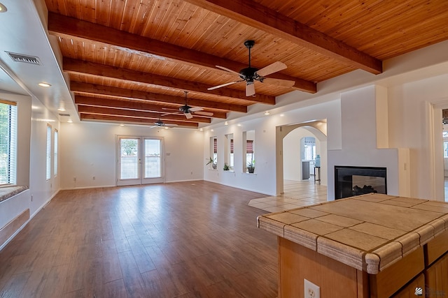 unfurnished living room with beam ceiling, wood-type flooring, wooden ceiling, and a multi sided fireplace