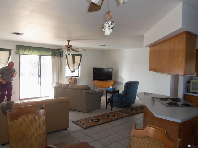 living area with visible vents, ceiling fan, and light tile patterned floors